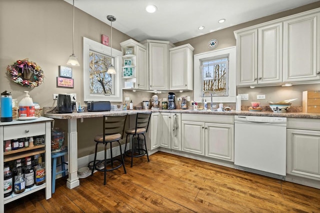 kitchen featuring pendant lighting, a sink, hardwood / wood-style floors, white cabinets, and dishwasher