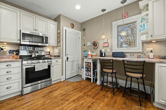 kitchen with white cabinetry, wood finished floors, appliances with stainless steel finishes, and pendant lighting