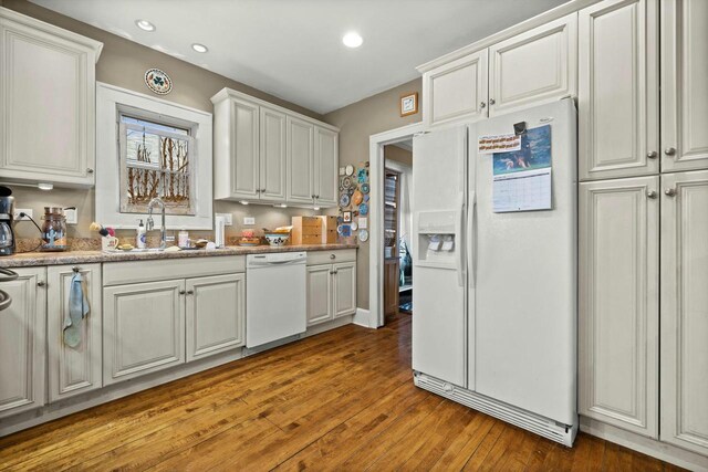 kitchen with hardwood / wood-style floors, white appliances, recessed lighting, a sink, and white cabinets