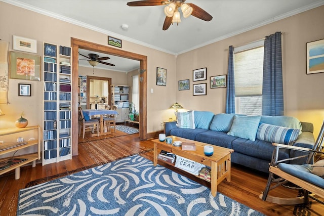 living area with ornamental molding, wood finished floors, baseboards, and ceiling fan