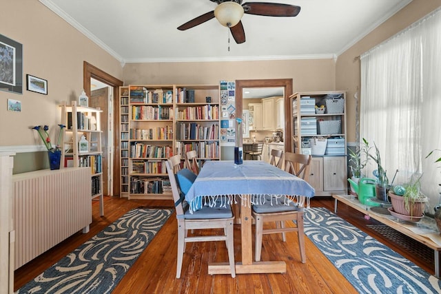 dining space with wood finished floors, a ceiling fan, and crown molding