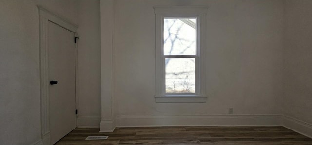 unfurnished room with visible vents, wood finished floors, and baseboards