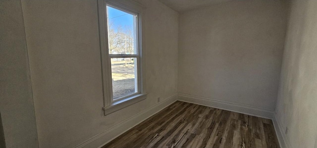 empty room featuring baseboards and dark wood-style flooring