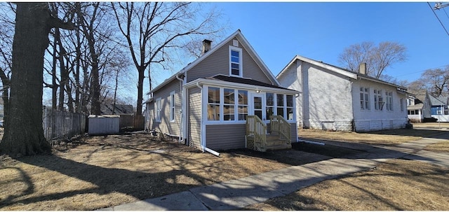 view of front of property featuring fence, a sunroom, and a chimney