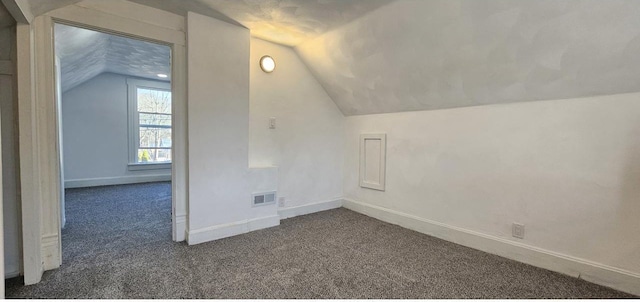 bonus room featuring vaulted ceiling, visible vents, baseboards, and dark colored carpet