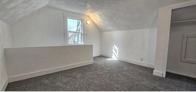 additional living space featuring carpet flooring, baseboards, and vaulted ceiling