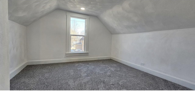 bonus room featuring lofted ceiling, carpet flooring, baseboards, and a textured ceiling