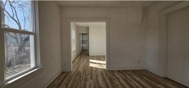 spare room featuring baseboards and dark wood-style flooring