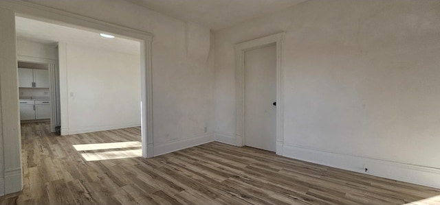 spare room with baseboards and wood finished floors