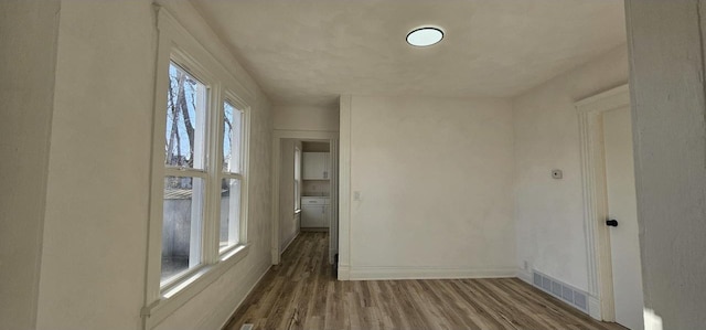 spare room featuring visible vents, baseboards, and wood finished floors