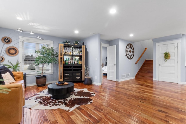 living area with stairway, wood finished floors, visible vents, baseboards, and recessed lighting