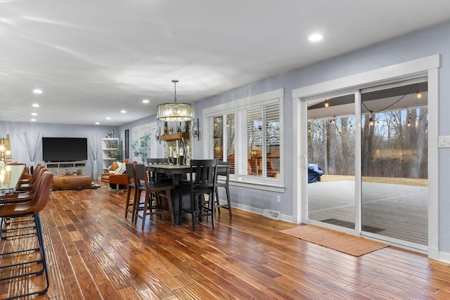 unfurnished dining area with a notable chandelier, recessed lighting, baseboards, and wood finished floors