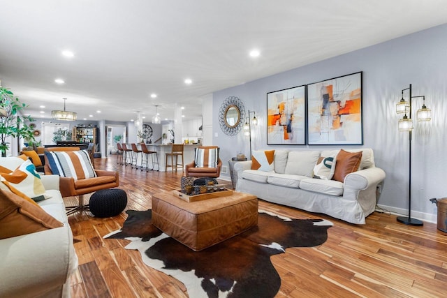 living room with a notable chandelier, recessed lighting, baseboards, and light wood finished floors