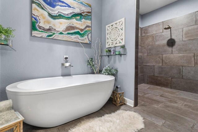 bathroom with tiled shower and a freestanding bath