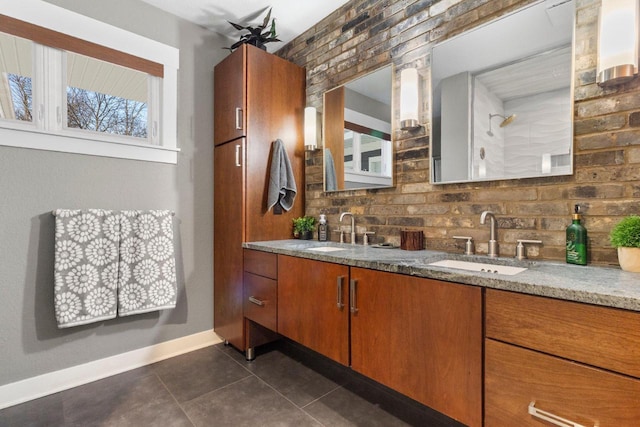 bathroom featuring a sink, brick wall, double vanity, and tile patterned flooring