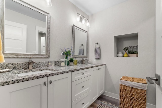 full bathroom with double vanity, wood finished floors, baseboards, and a sink