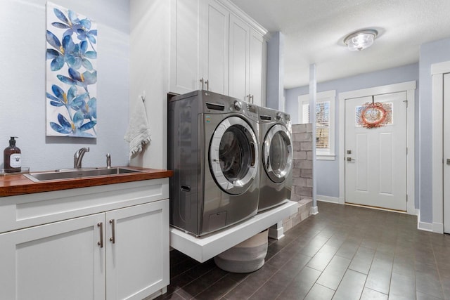 washroom featuring washing machine and clothes dryer, cabinet space, baseboards, and a sink