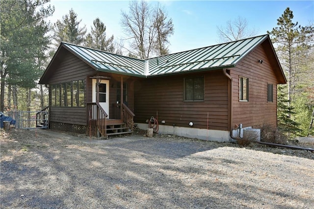 rustic home featuring metal roof, a sunroom, and a standing seam roof