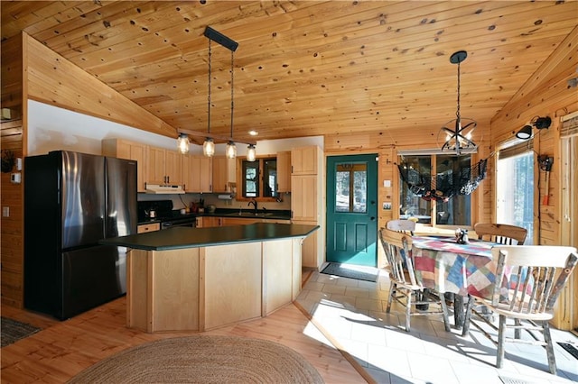 kitchen with light brown cabinets, a sink, dark countertops, freestanding refrigerator, and exhaust hood