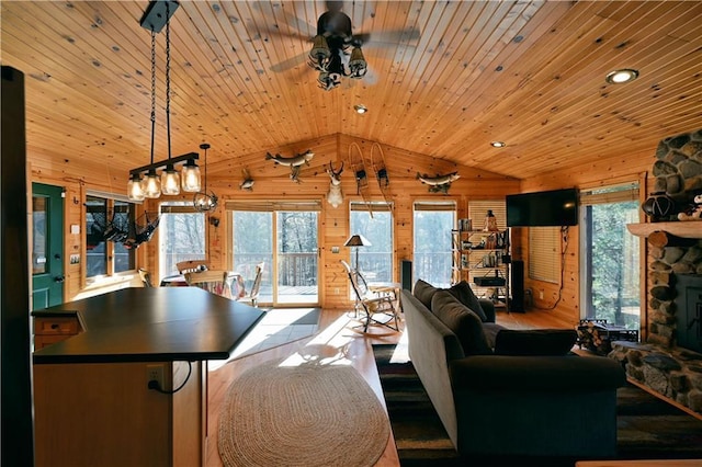 living area featuring a stone fireplace, wood walls, wood ceiling, ceiling fan, and vaulted ceiling