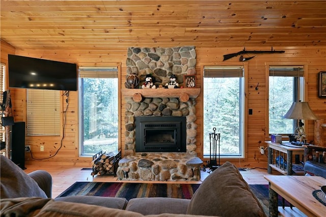 living room featuring a stone fireplace, hardwood / wood-style flooring, lofted ceiling, and wood walls