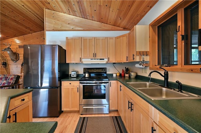 kitchen featuring light brown cabinets, a sink, vaulted ceiling, under cabinet range hood, and appliances with stainless steel finishes