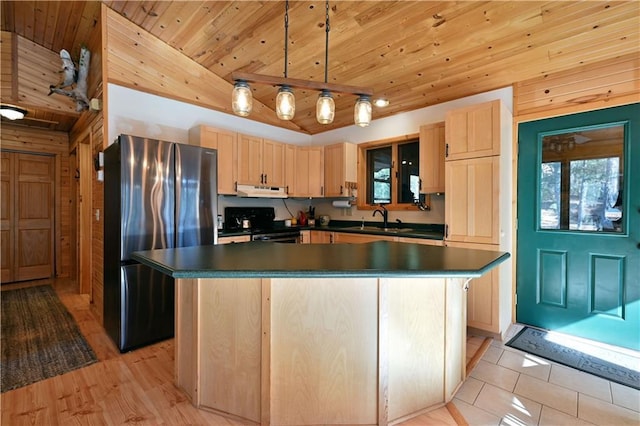 kitchen with light brown cabinetry, a sink, dark countertops, freestanding refrigerator, and gas stove