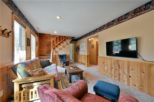 carpeted living area featuring stairs, wooden walls, recessed lighting, and wainscoting