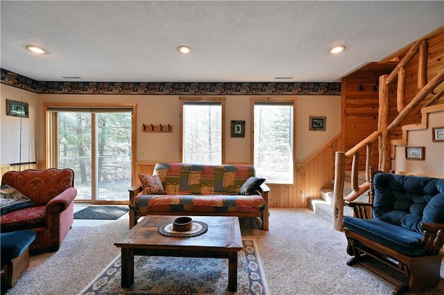 living room featuring a textured ceiling, stairway, carpet floors, and wainscoting