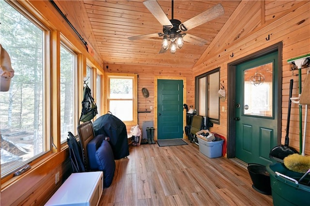 entryway with light wood-style floors, wood ceiling, wood walls, and vaulted ceiling