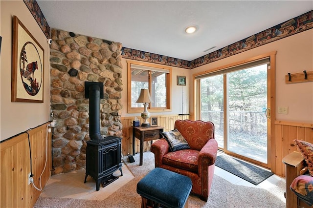 living area with a wainscoted wall and a wood stove