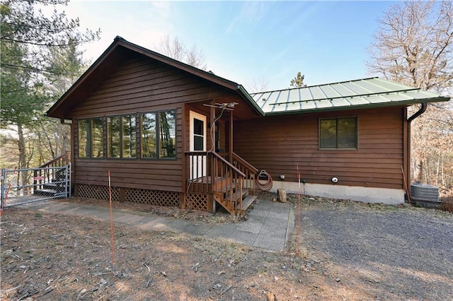 rustic home with metal roof, a sunroom, cooling unit, and a standing seam roof