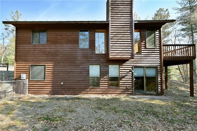 back of property featuring a deck, a chimney, and fence