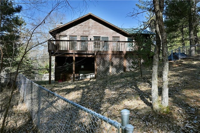 rear view of house featuring a wooden deck and a fenced backyard