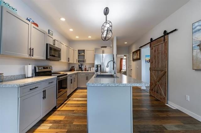 kitchen featuring a sink, open shelves, wood finished floors, a barn door, and appliances with stainless steel finishes