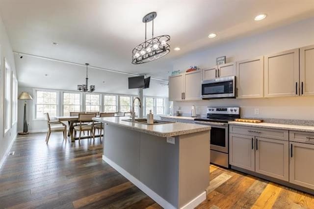 kitchen featuring a notable chandelier, gray cabinets, appliances with stainless steel finishes, and an island with sink