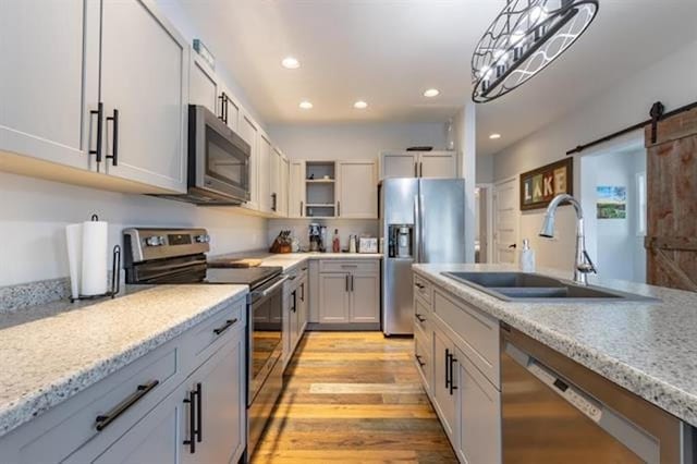 kitchen featuring open shelves, light wood-style flooring, recessed lighting, a sink, and appliances with stainless steel finishes