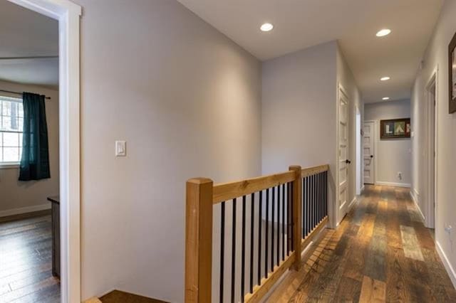 corridor featuring hardwood / wood-style floors, recessed lighting, an upstairs landing, and baseboards