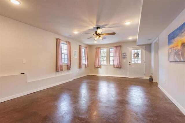 unfurnished living room with baseboards, concrete floors, and ceiling fan