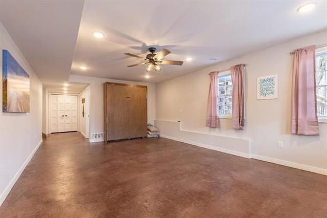 interior space with plenty of natural light, baseboards, ceiling fan, and finished concrete floors