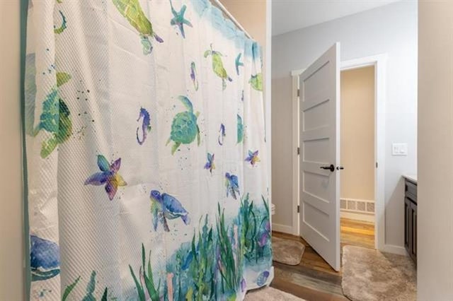 bathroom featuring curtained shower, vanity, baseboards, and wood finished floors