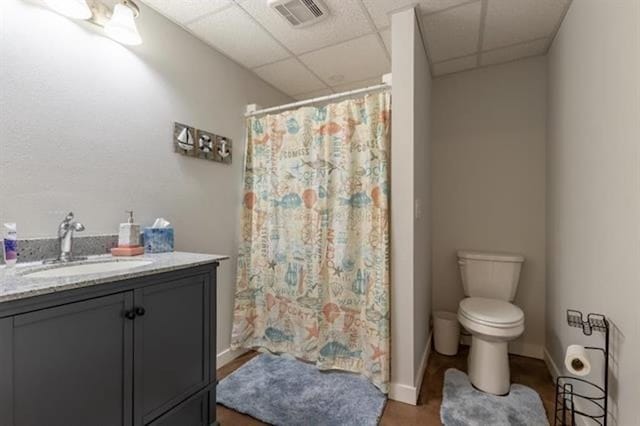 bathroom featuring vanity, a shower with shower curtain, visible vents, a drop ceiling, and toilet