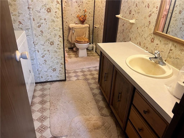 bathroom with wallpapered walls, toilet, and vanity