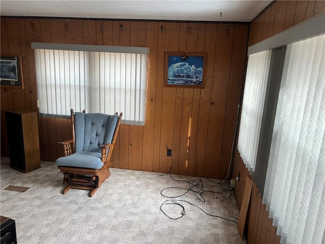 sitting room featuring wooden walls and carpet