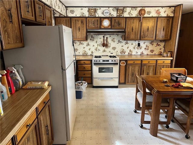 kitchen with under cabinet range hood, gas range gas stove, light floors, and light countertops