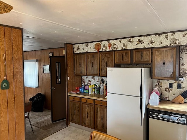 kitchen featuring freestanding refrigerator, dark brown cabinetry, light countertops, dishwashing machine, and light floors