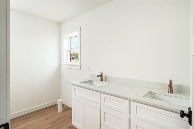 bathroom featuring wood finished floors, baseboards, and a sink