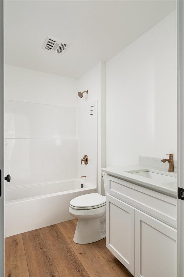 bathroom featuring hardwood / wood-style floors, vanity, visible vents, shower / tub combination, and toilet