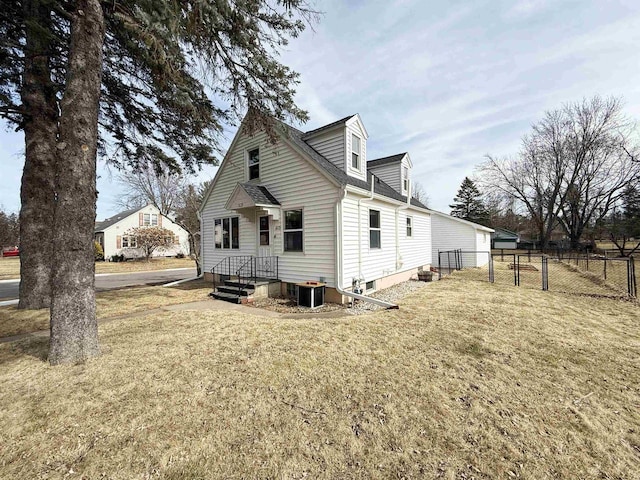 rear view of property featuring central AC unit, a yard, and fence