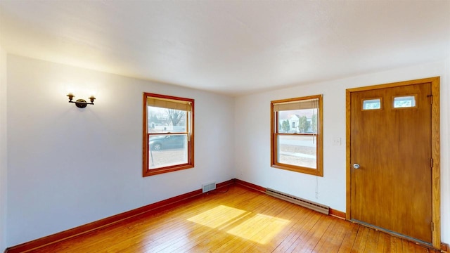 foyer entrance featuring plenty of natural light, light wood-type flooring, baseboards, and a baseboard radiator